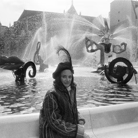 Niki de Saint Phalle assise devant la Fontaine Stravinsky, près du Centre Pompidou à Paris, entourée de ses sculptures en mouvement.