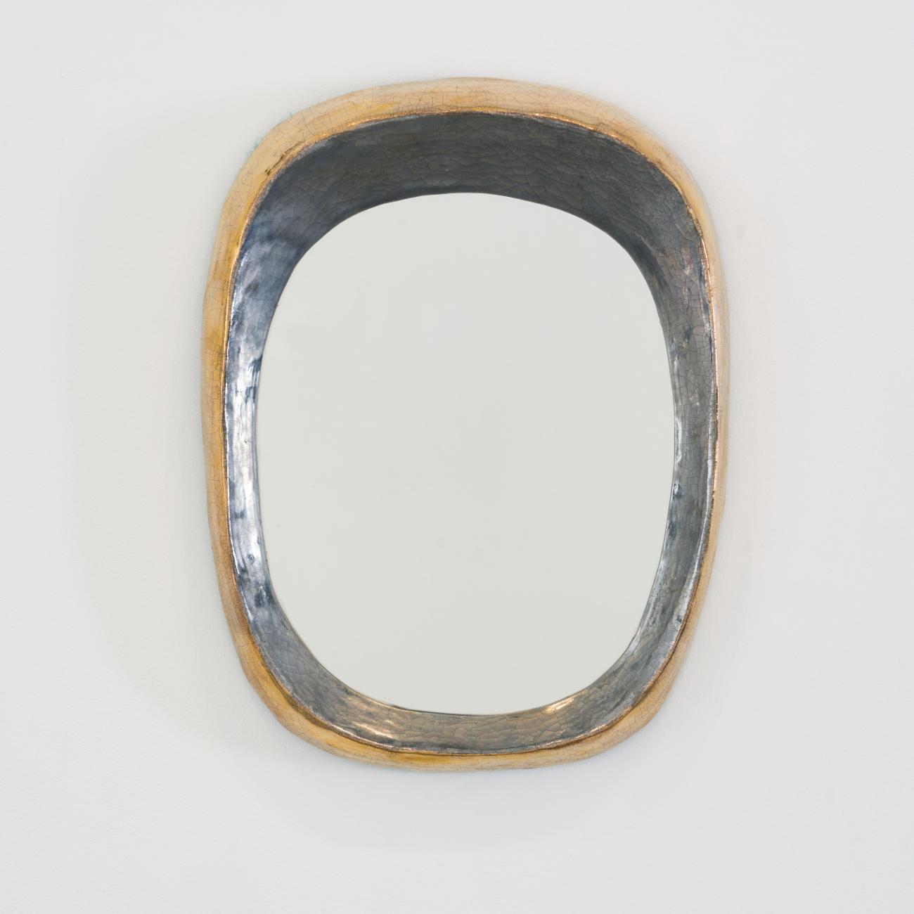 Grand miroir mural de forme libre par Mithé Espelt, vers 1948. Céramique estampée rehaussée de platine au four, contours irréguliers aux reflets dorés et argentés, exemplaire exceptionnel.