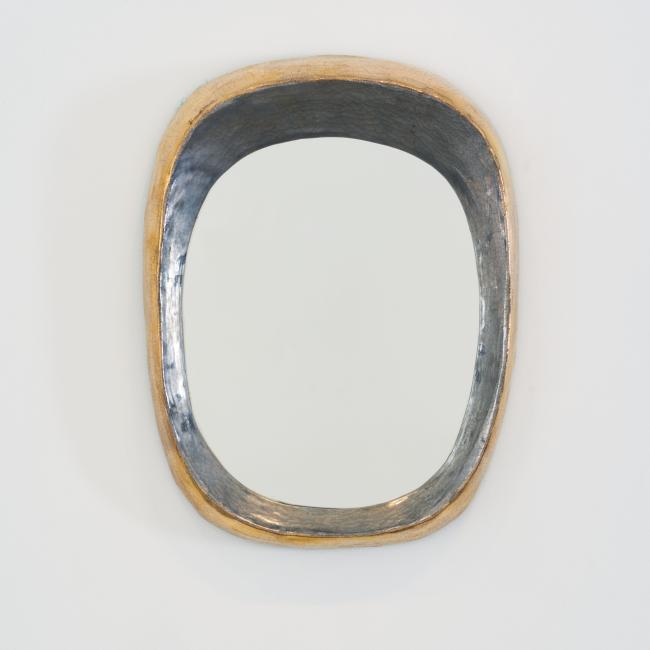Grand miroir mural de forme libre par Mithé Espelt, vers 1948. Céramique estampée rehaussée de platine au four, contours irréguliers aux reflets dorés et argentés, exemplaire exceptionnel.