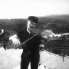 Arman sur la Grande Muraille de Chine, mimant un geste de violon.